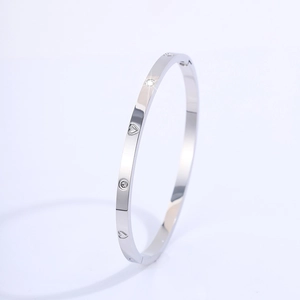 Detail view of silver titanium steel bangle with heart engraving and embedded crystals