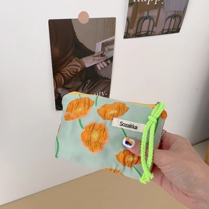 Close-up of mint canvas cosmetic pouch with orange floral print and neon green zipper cord