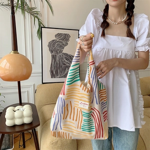 Close-up of colorful striped canvas tote bag with textured corduroy fabric details