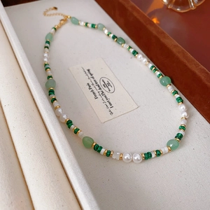 Close-up of malachite beads and pearls on an elegant vintage-style necklace with gold clasp