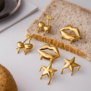Macro view of gold liquid cherry earrings with metallic drip effect on textured surface