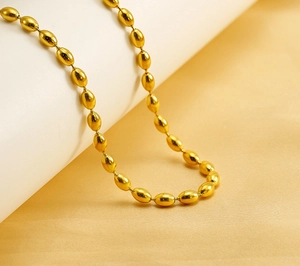 Macro detail of oval gold bead chain necklace showcasing glossy polished finish