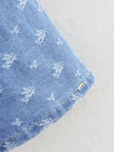 Dettaglio ravvicinato del tessuto denim blu con motivo a stelle bianche e doppia cucitura