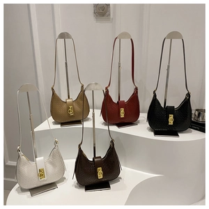 Detail view of five hobo handbags in various colors featuring croc-embossed leather and gold locks