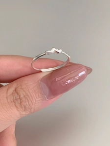 Close-up of minimalist S925 silver heart ring with small diamond on finger
