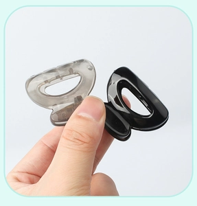 Close-up of mini semi-circle hair clips in matte black and translucent grey colors