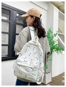 Detail of white floral backpack with blue tulips featuring padded straps and side pocket