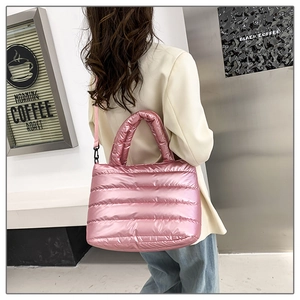 Metallic pink quilted tote bag shown on person with crossbody strap and puffer texture