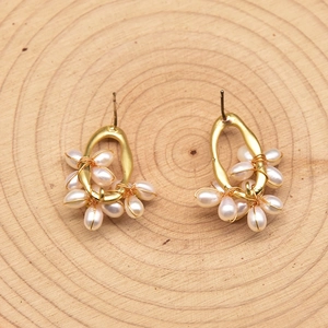 Elegant gold metal pearl cluster earrings with white oval pearls on natural wood base
