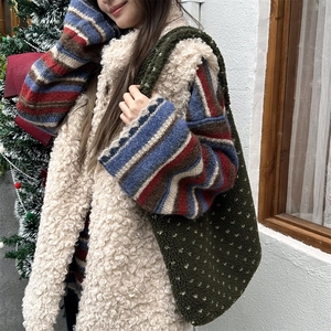 Detail of emerald green faux fur tote bag with heart pattern and white fleece vest