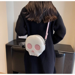 Detail shot of a white and pink skull-shaped crossbody bag shown on a model