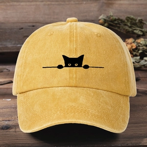 Close-up of a yellow cotton baseball cap featuring a cute black cat embroidery on a wood surface