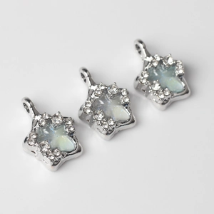 Macro shot of star pendants with silver finish, inlaid crystals and opal-like stones
