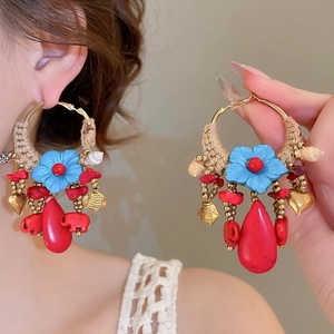 Close-up of bohemian hoop earrings with blue flowers and woven beige rope details