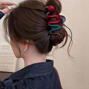 Detail of wavy colorful hair claw clip with red bead accent on model hairstyle