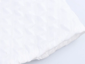Close-up of white quilted fabric detail featuring diamond pattern and stitched edges