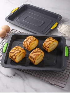 Detail of square silicone baking pan with colorful handles and fresh Swiss roll cake