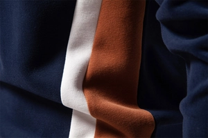 Close-up of navy, white, and orange-brown patchwork cotton fabric showing fine stitching