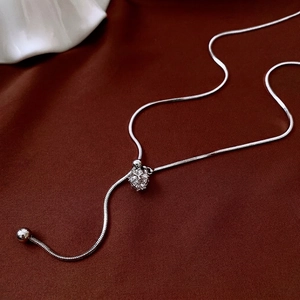Silver snake chain necklace with round zircon pendant on elegant red silk background