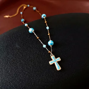Vintage-Goldkette mit Kreuzanhänger und blauen Marmorperlen auf dunklem Grund