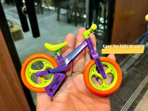 Miniature purple balancing bike toy held by hand to show its portable compact size