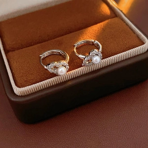 Detailed close-up of zircon hollow gourd earrings with pearls in a luxury jewelry box