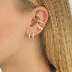 Elegant 18K gold pearl huggie earrings and ear cuff set shown on a female model