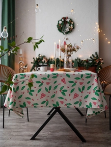 Close-up of Christmas tablecloth with holly leaves and red berry heart print