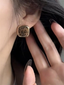 Close-up of leopard print square stud earrings with vintage gold metal border and velvet texture