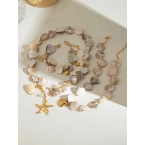 Detail of seashell necklace with gold starfish, conch pendants and white pearls