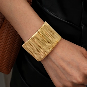Detailed view of wide gold layered wire wrap open cuff bracelet on female model