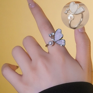 Bague papillon argentée avec perle et zircone sur fond de couleur chaude