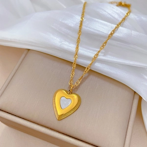 Macro detail of gold-plated heart pendant necklace with white shell inlay on silk cloth