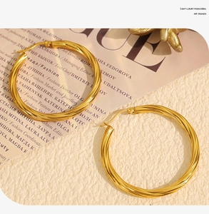 Detailed view of 18k gold twisted hoop earrings with elegant glossy texture on a magazine