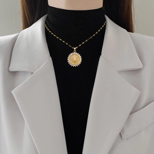 Luxurious gold lion head pendant necklace with rhinestones worn by a model in a white blazer