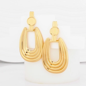Exaggerated geometric gold metal earrings with striped texture on white display