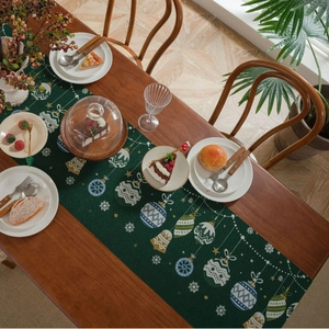 Close-up of green Christmas table runner with festive jacquard patterns and tassels