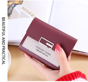 Close-up of burgundy and off-white women's tri-fold wallet with Forever Young metal plate