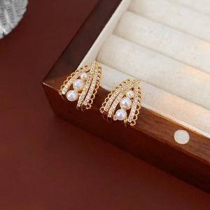 Macro shot of French vintage pearl earrings with zircon inlay on dark wood background