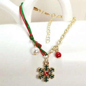 Close-up of Christmas bracelet with snowflake charm, red-green rope, and gold chain detail
