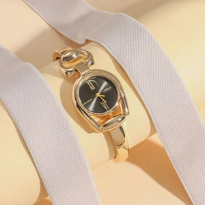 Close-up of gold-tone watch with black dial and stirrup-shaped lugs for women