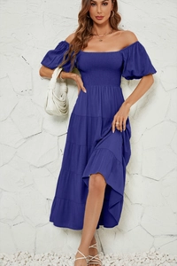 Détail de robe bleue à épaules dénudées avec manches bouffantes sur un mur en pierre