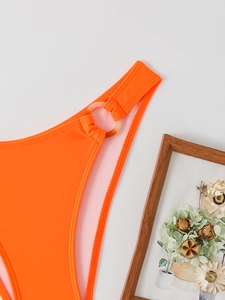 Detail of bright orange bikini bottom featuring a tortoiseshell resin ring connector