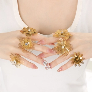 Détail du lot de cinq bagues fleurs dorées avec perles et strass portées par un mannequin