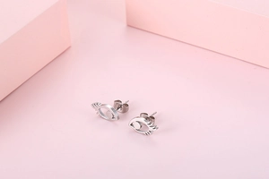 Detail of silver eye-shaped stud earrings in polished metal on a pink background