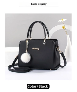 Detail of black crossbody bag with gold logo, heart pendant and white fur pompom charm