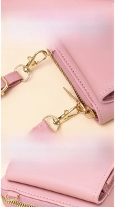 Detail view of the detachable golden metal clasp on a pink leather crossbody phone bag