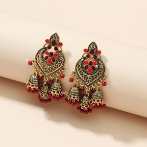 Detail of bohemian gold earrings with red heart pendants, enamel beads and small bell tassels