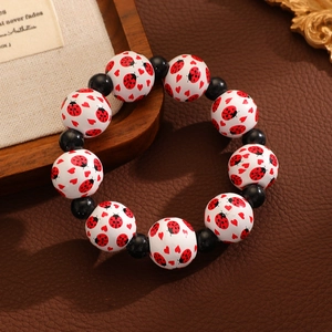 Détail du bracelet perlé avec motifs coccinelle et cœur sur fond en cuir sombre