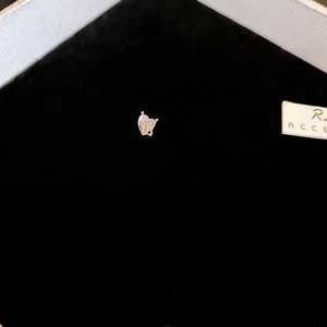 Detailed close-up of golden heart-shaped butterfly stud earrings on a black jewelry box